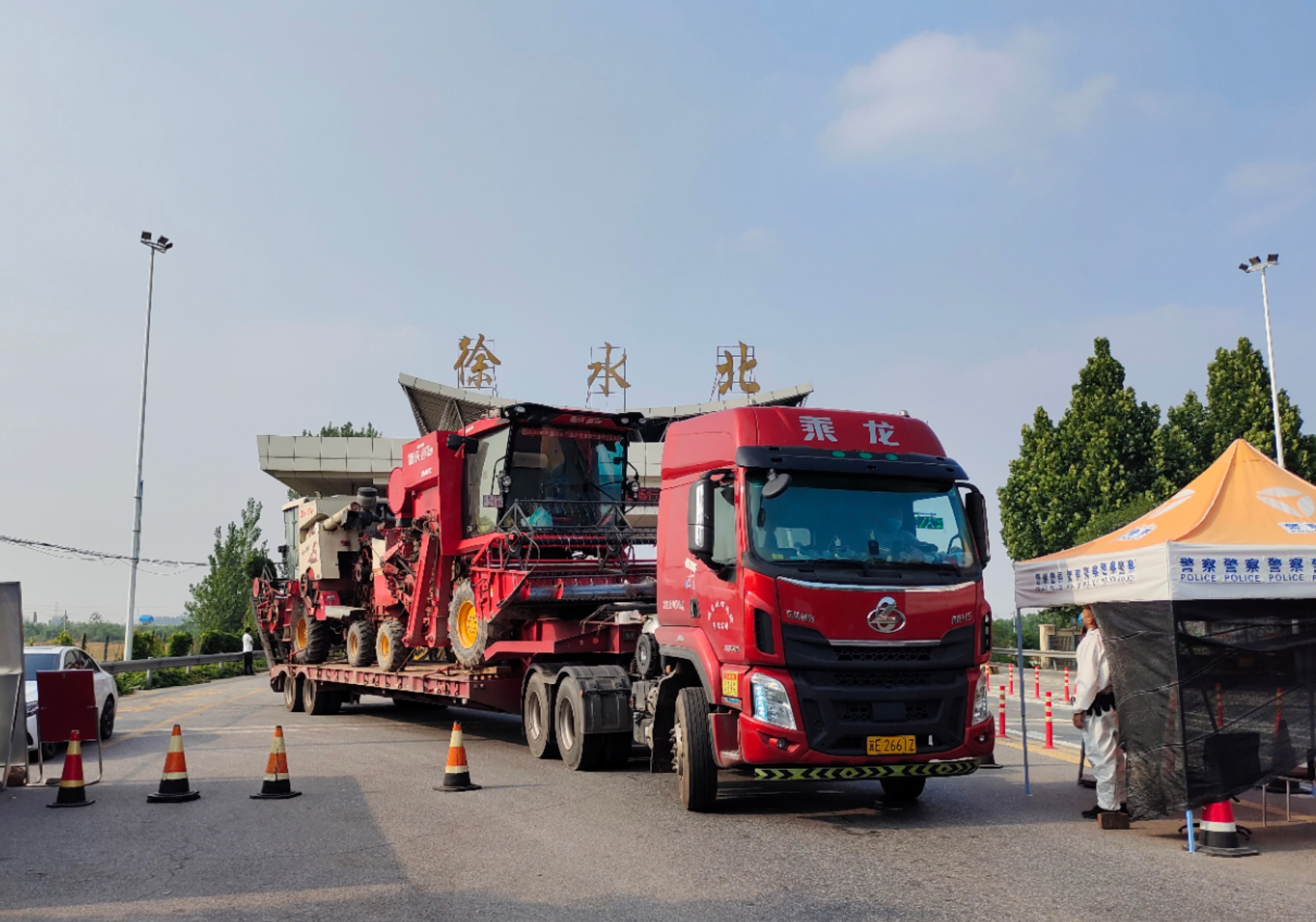 装载两辆收割机的大货车驶出荣乌高速徐水出口。李月英 摄
